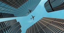 Airplane flies over skyscrapers in modern city