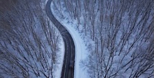Winding forest road covered with snow aerial winter footage