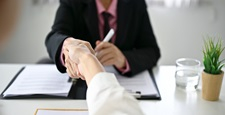 Close-up image of a candidate shaking hands with a businesswoman after a job interview